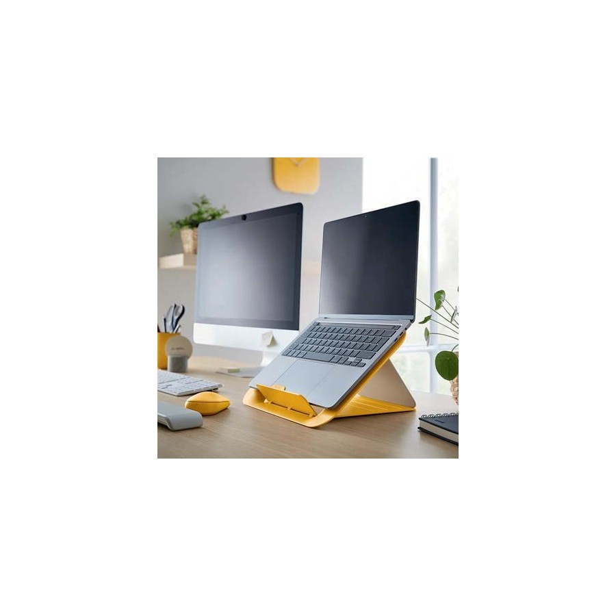 Laptop na podstawce Leitz Cosy w kolorze żółtym, obok monitor. Wszystko stoi na biurku.